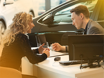 women having a conversation with a car dealership worker at a desk