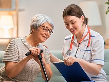 older lady with a cane talking to a woman doctor